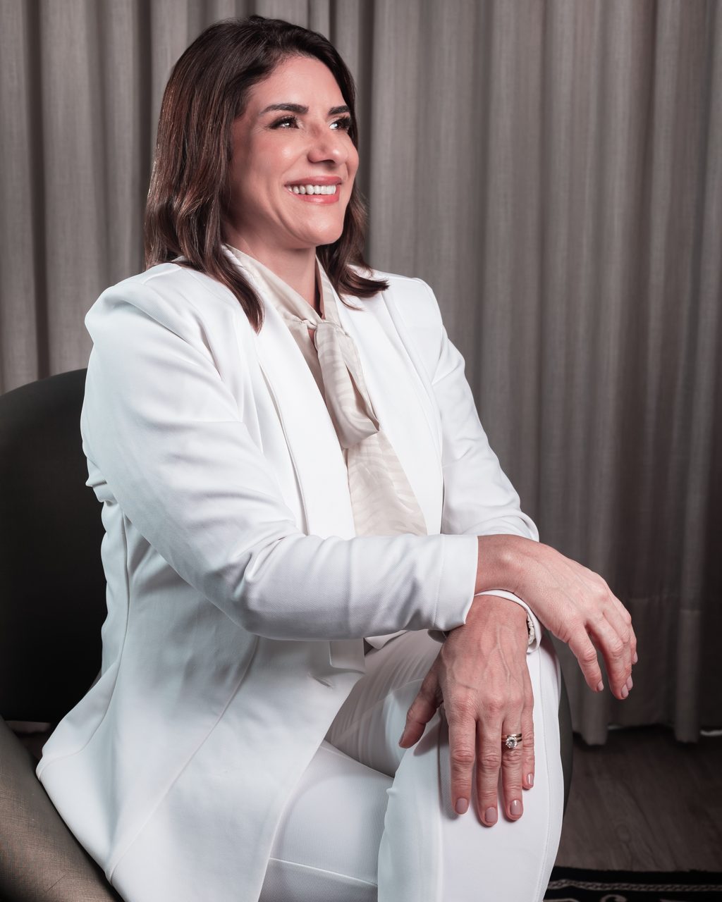 Dra. Glicéria Maria de Castro Tarachuk sentada, em traje clínico branco