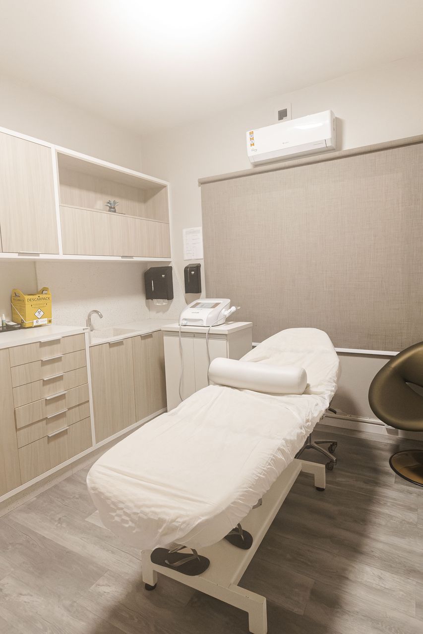 Sala de procedimentos da Corpo & Forma, com maca clínica preparada e bancada de apoio