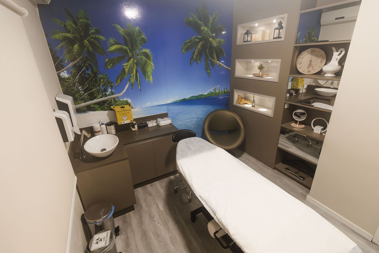 Sala de tratamento da Corpo & Forma com mural de praia, maca preparada e bancada de apoio